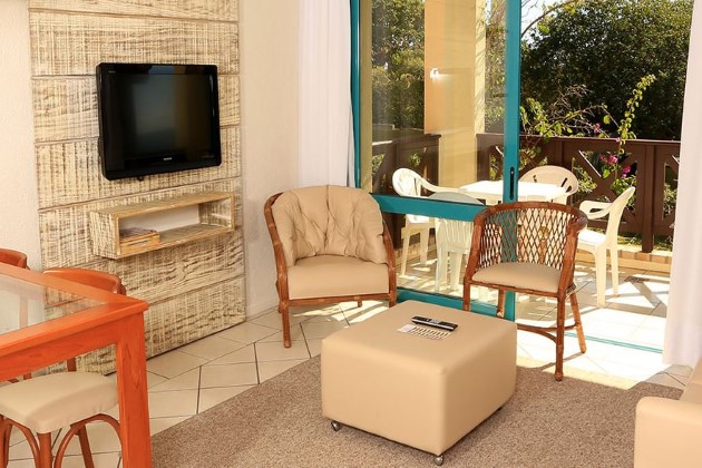 Foto de um cômodo com acesso a sacada, duas cadeiras e tv