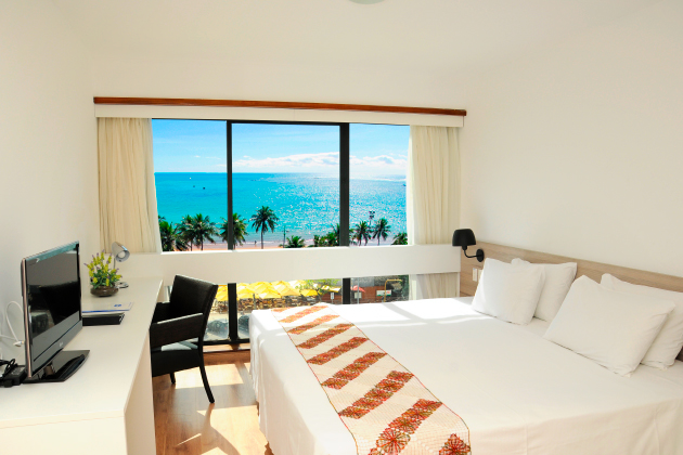 Imagem do quarto de frente ao mar contendo uma cama de casal e uma tv 