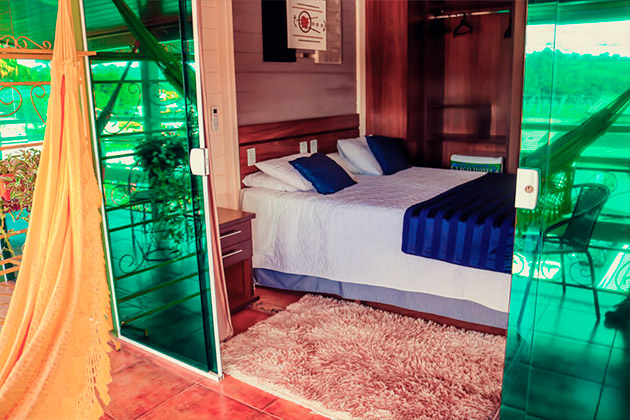 imagem do lado de fora do quarto mostrando uma rede amarela e a cama após a porta de correr.